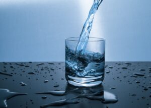 Water being poured into a glass on a wet table.